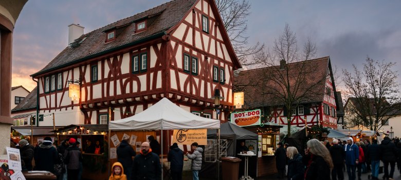 Menschen stehen in Winterjacken auf dem Weihnachtsmarkt