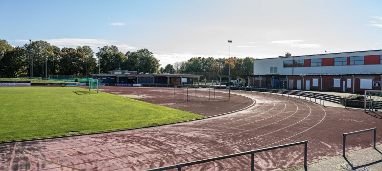 Ein Rasensportplatz mit Laufbahn und Gebäude im Hintergrund
