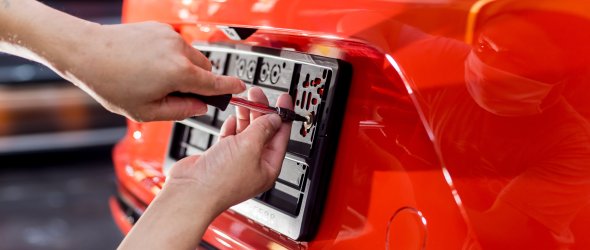 Technician changing car plate number in service center.