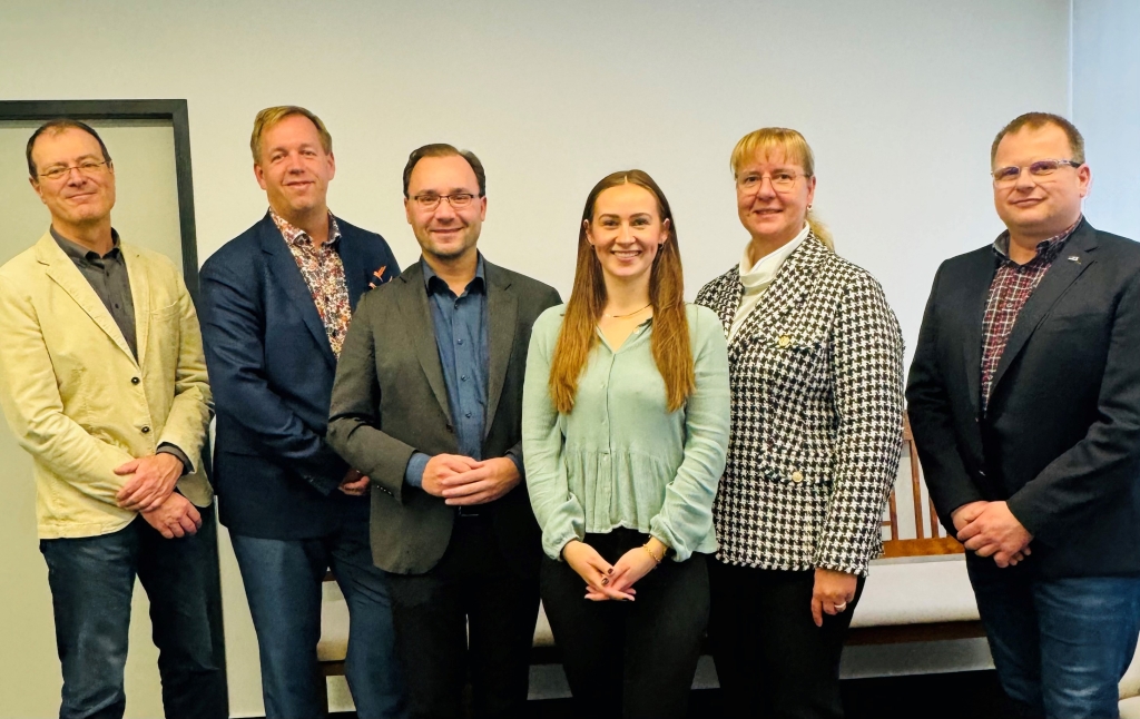 Das Bild zeigt sechs Personen in einem Raum. In der Mitte steht Tabea Auffermann. Sie hat ihre Ausbildung sehr gut abgeschlossen. Bürgermeister Dr. Alexander Krey steht neben ihr. Alle Personen lächeln und schauen in die Kamera.