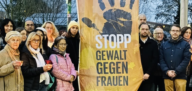 Eine Gruppe Menschen steht draußen vor einer Fahne. Auf der Fahne steht "Stopp Gewalt gegen Frauen". Bürgermeister Dr. Alexander Krey ist dabei. Einige Menschen halten Kerzen in der Hand.