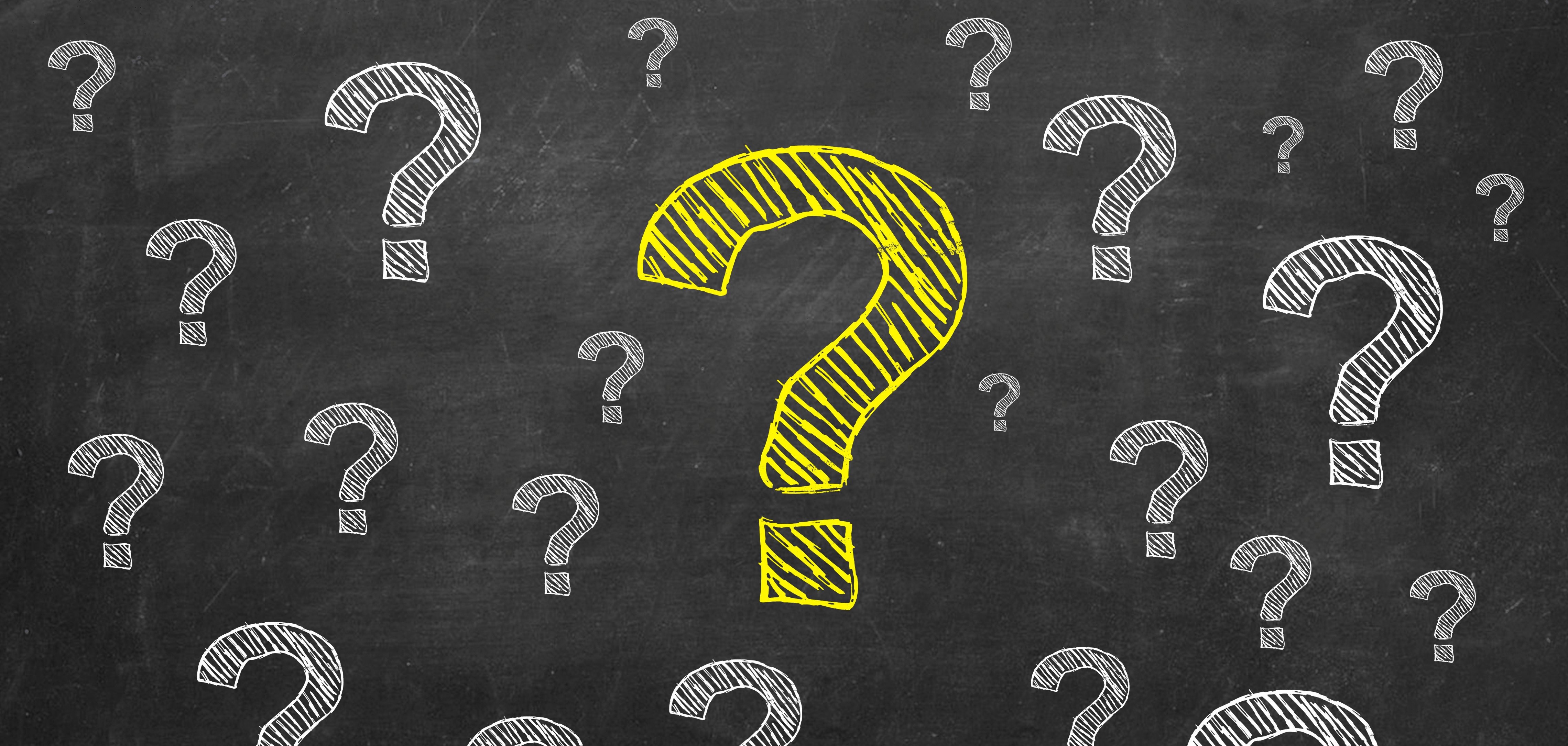 Auf dem Bild sieht man eine schwarze Tafel. Darauf sind viele weiße Fragezeichen gemalt. In der Mitte ist ein großes, gelbes Fragezeichen. Es fällt sofort auf. Die Fragezeichen stehen für viele Fragen oder Unklarheiten.