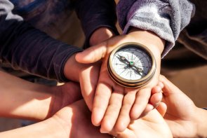 children holding a compass pointing north